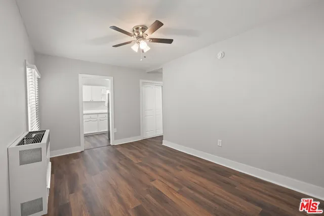 an empty room with wooden floor closet and windows