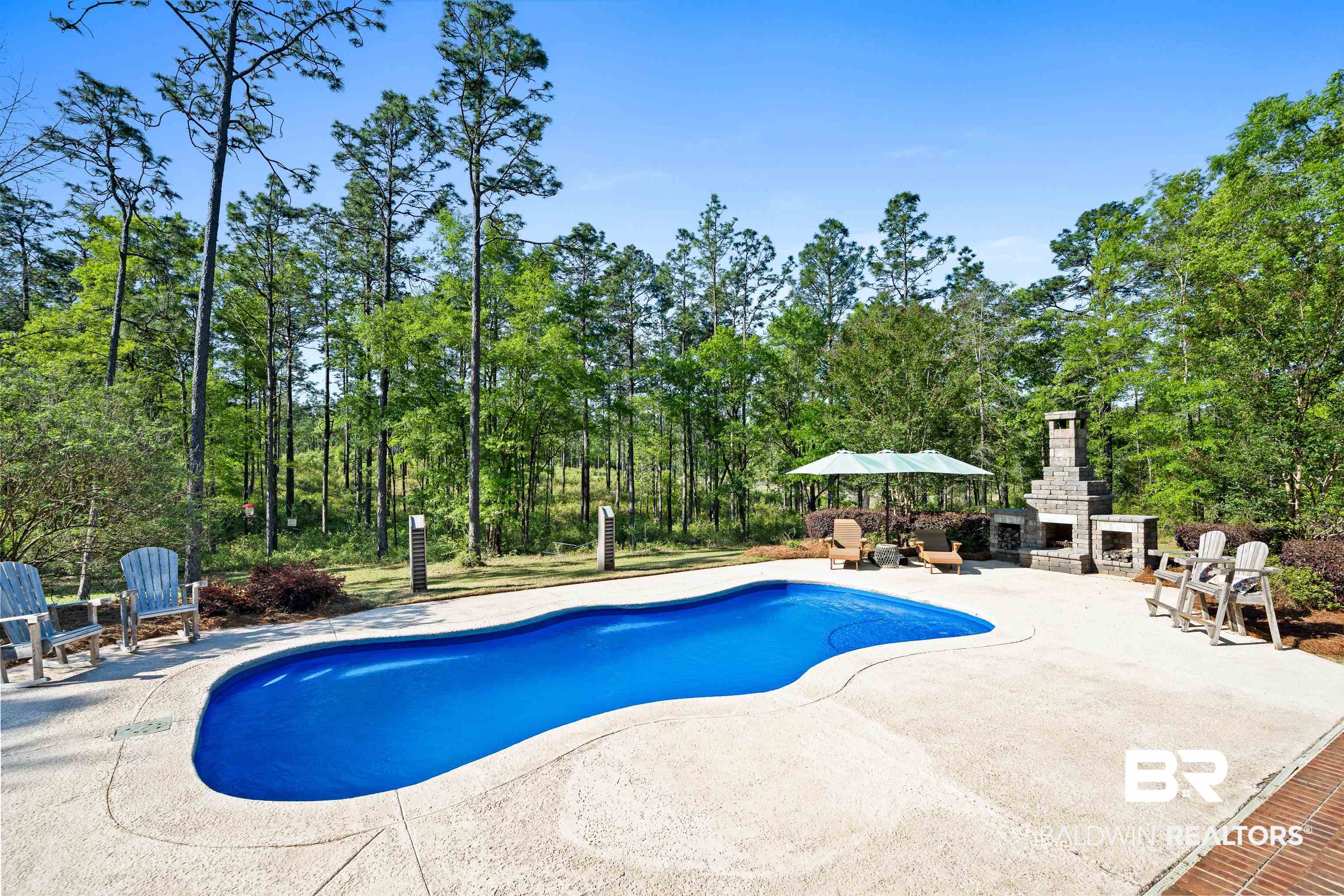 47252 Emmons Road Bay Minette, AL 36507 - Photo 36 of 50 Outdoor pool featuring an outdoor stone fireplace, a patio area, and view of wooded area