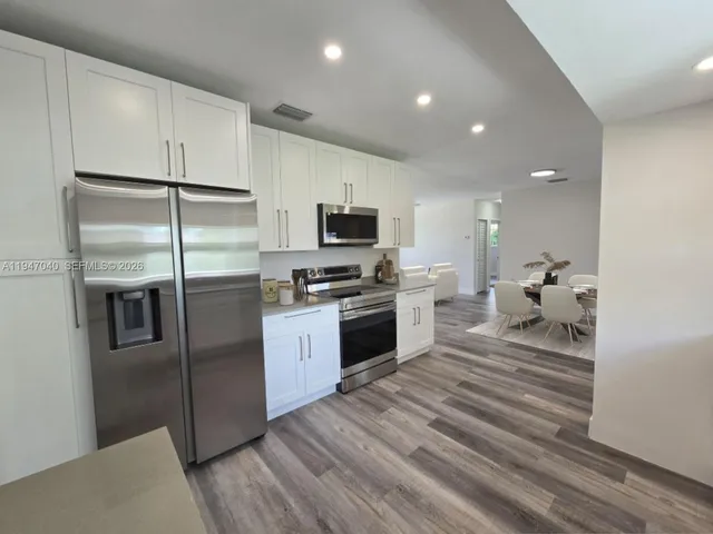 a kitchen with granite countertop a refrigerator a stove top oven a sink and dishwasher