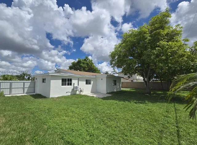 a view of a house with a yard and a large tree