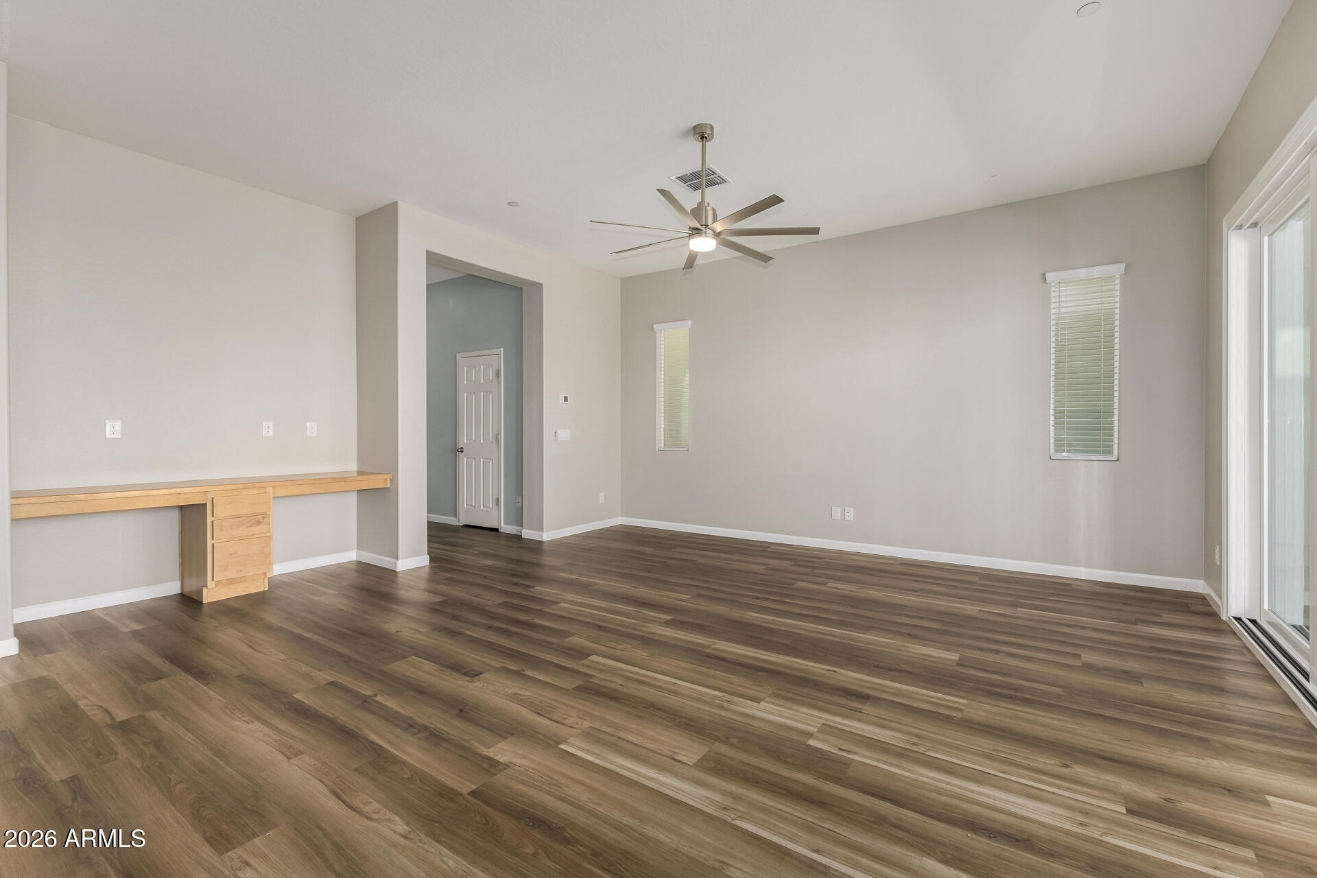 7358 West Phelps Road Peoria, AZ 85382 - Photo 6 of 28 a view of an empty room with wooden floor and a window