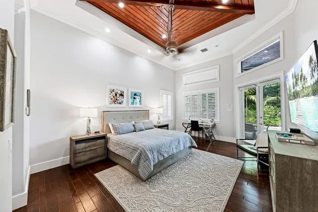 a bedroom with a bed wooden floor and a large window