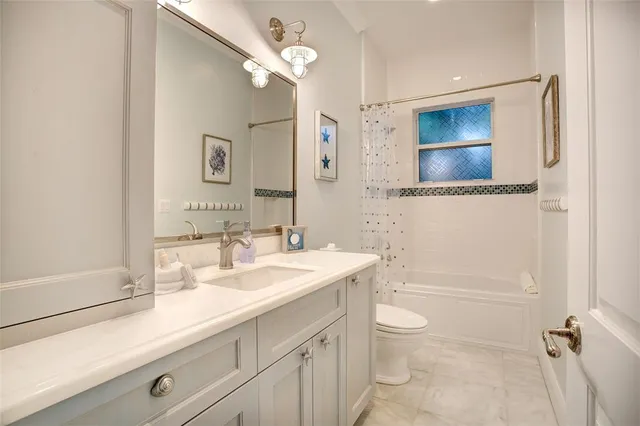 a bathroom with a granite countertop sink a toilet a mirror and shower