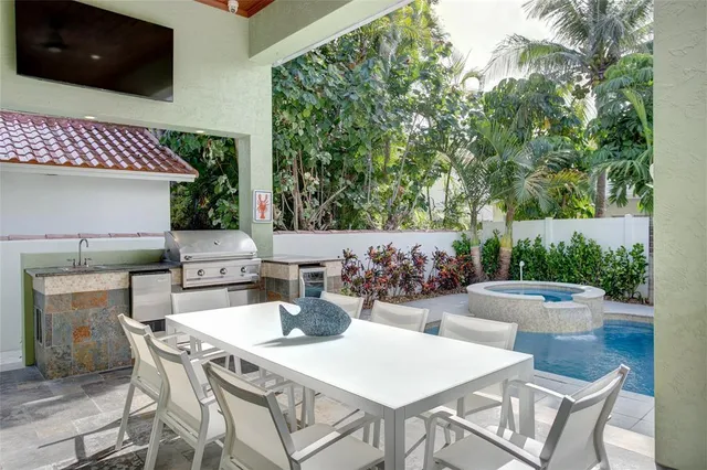 a view of swimming pool with lawn chairs plants and large trees