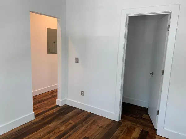 a view of an empty room with wooden floor and closet