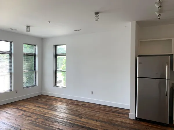 a view of an empty room with wooden floor and a window