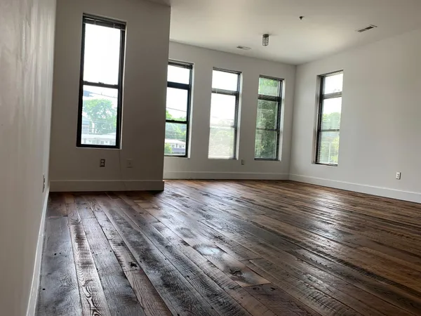an empty room with wooden floor and windows