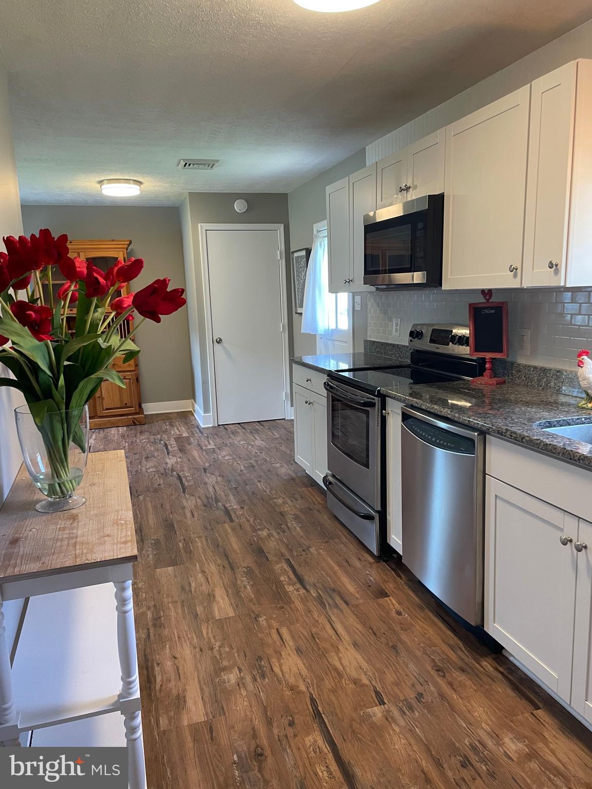 5 Oak Street Cambridge, MD 21613 - Photo 14 of 31 a kitchen with stainless steel appliances kitchen island granite countertop a stove a sink and a microwave