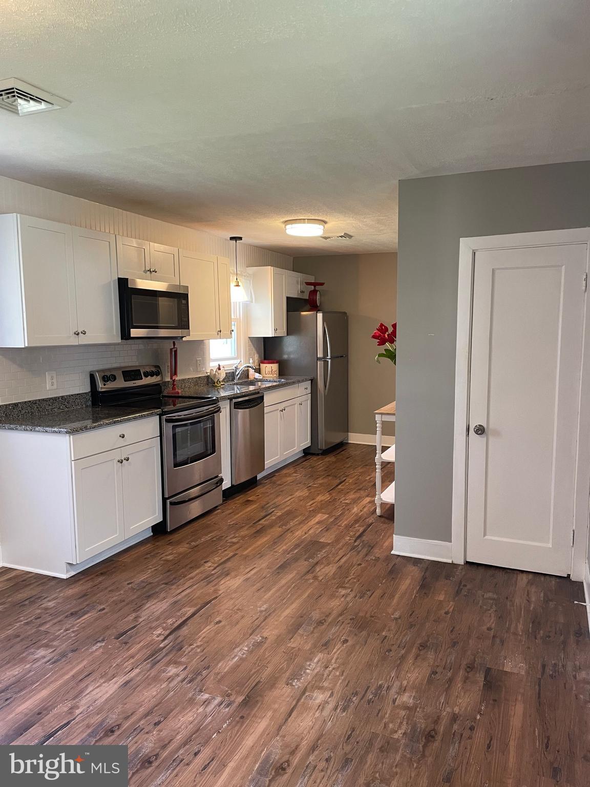 5 Oak Street Cambridge, MD 21613 - Photo 9 of 31 a kitchen with granite countertop a stove top oven and cabinets