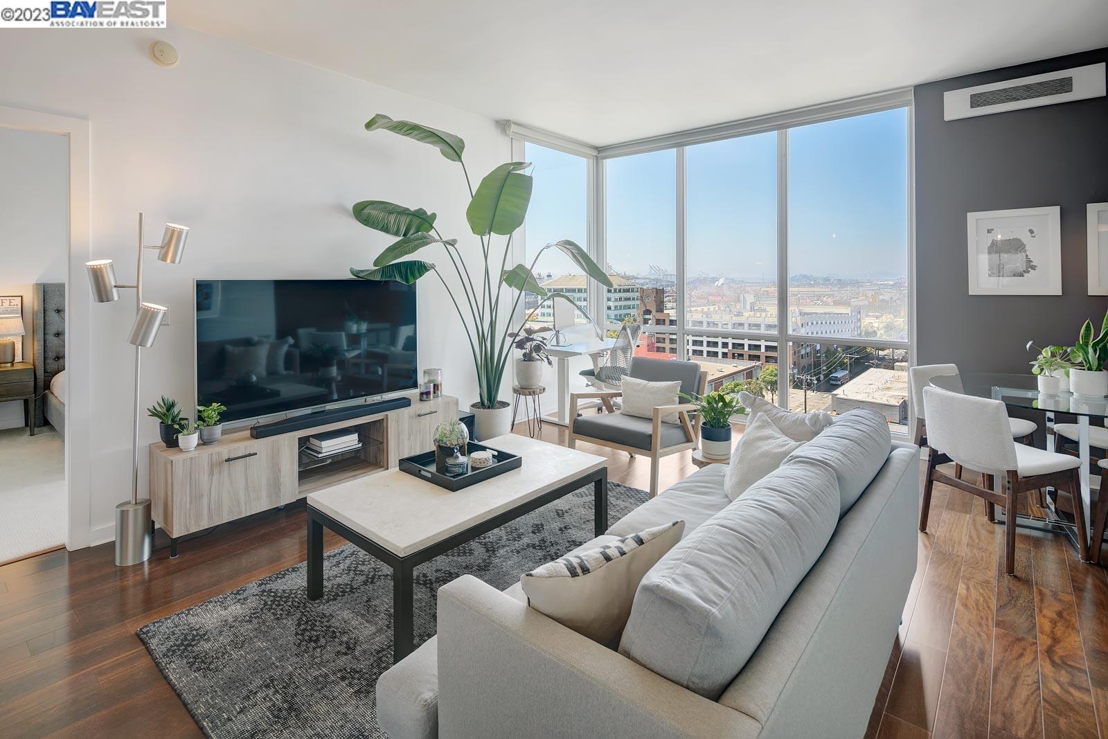 222 Broadway, Unit 1004 Oakland, CA 94607 - Photo 13 of 60 a living room with furniture a flat screen tv and a floor to ceiling window