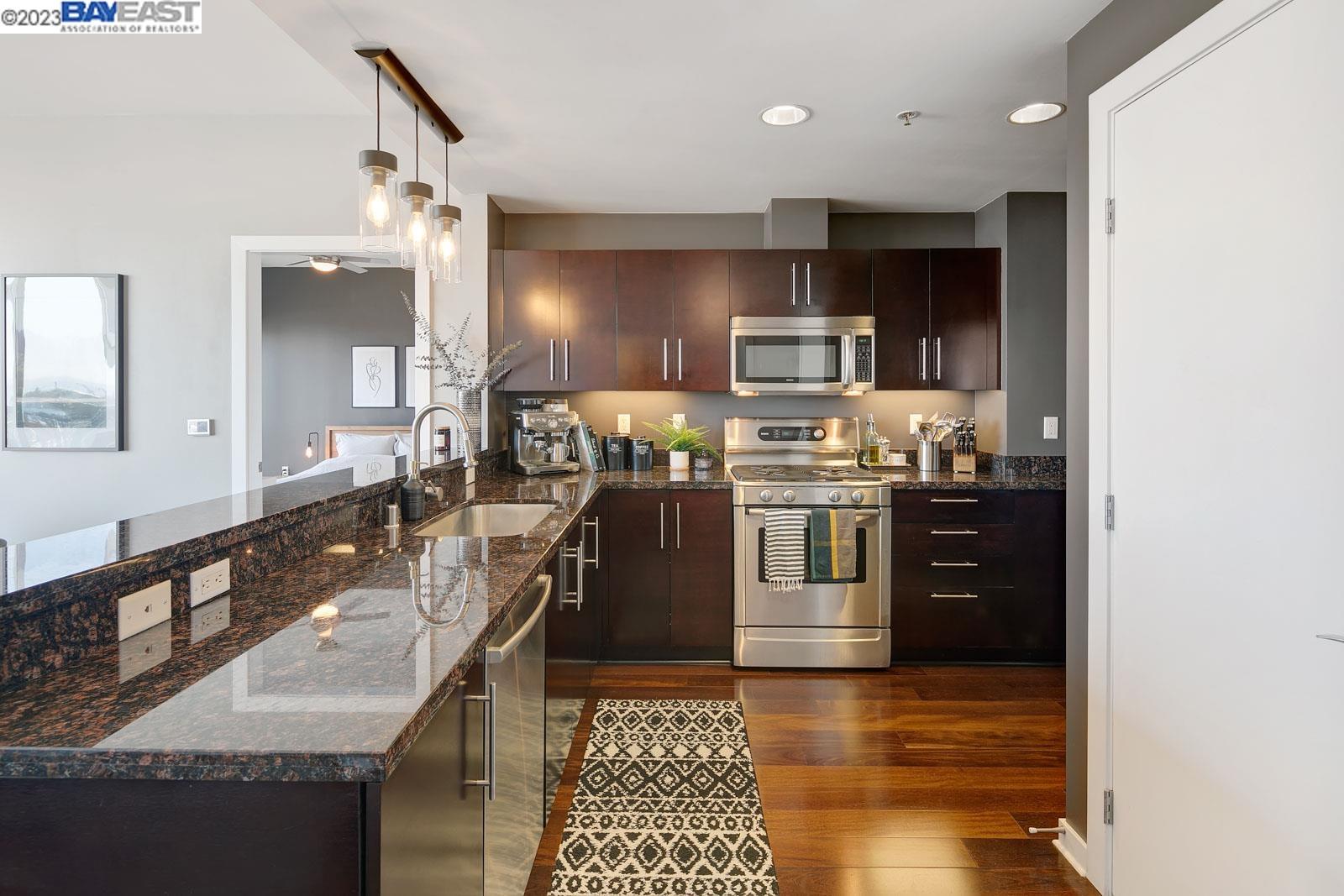 222 Broadway, Unit 1004 Oakland, CA 94607 - Photo 5 of 60 a kitchen with stainless steel appliances granite countertop a sink stove and refrigerator