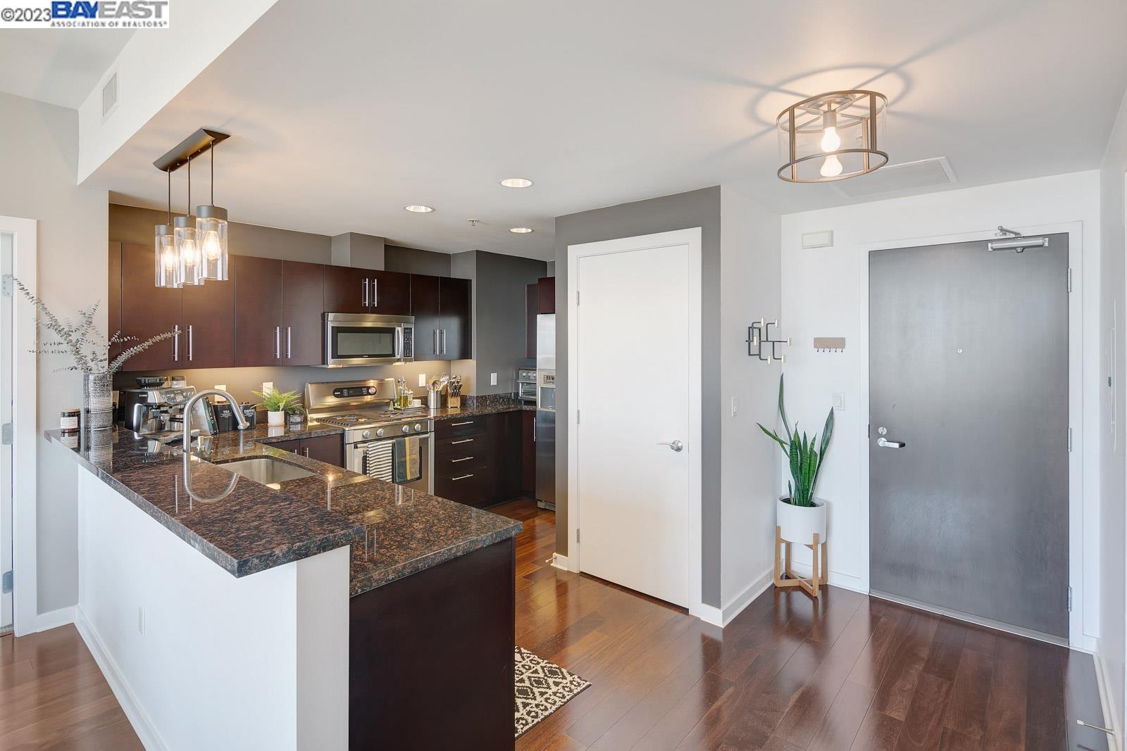 222 Broadway, Unit 1004 Oakland, CA 94607 - Photo 6 of 60 a kitchen with stainless steel appliances granite countertop a refrigerator a sink a stove and wooden floor