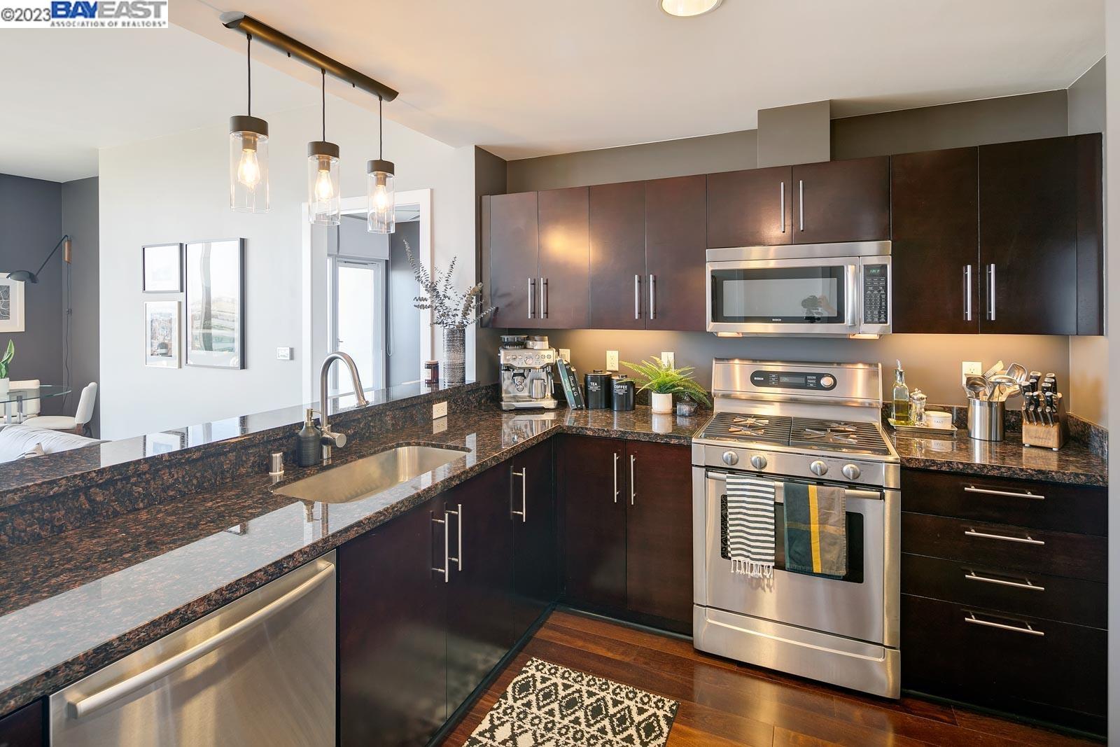 222 Broadway, Unit 1004 Oakland, CA 94607 - Photo 9 of 60 a kitchen with granite countertop stainless steel appliances and wooden cabinets