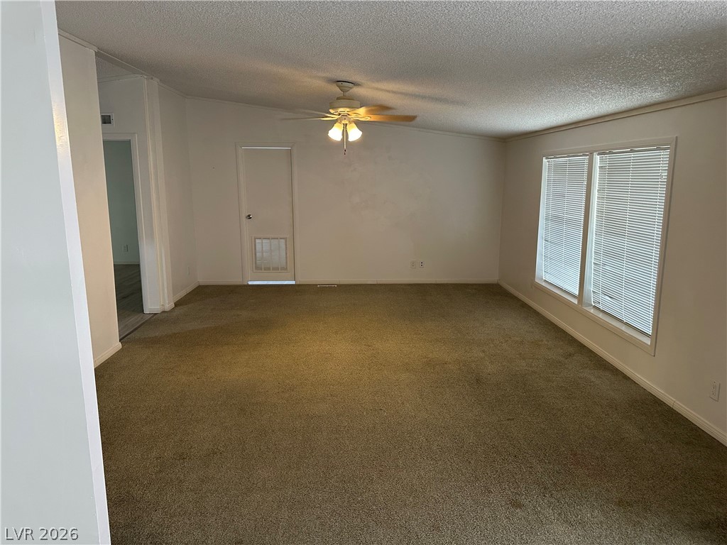 3270 West Simkins Road Pahrump, NV 89060 - Photo 27 of 36 An open living room area features carpet flooring and abundant natural light from large windows.