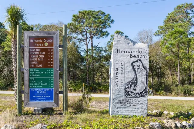 a sign board with a small yard and large trees