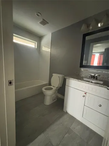 a bathroom with a granite countertop sink a toilet and mirror