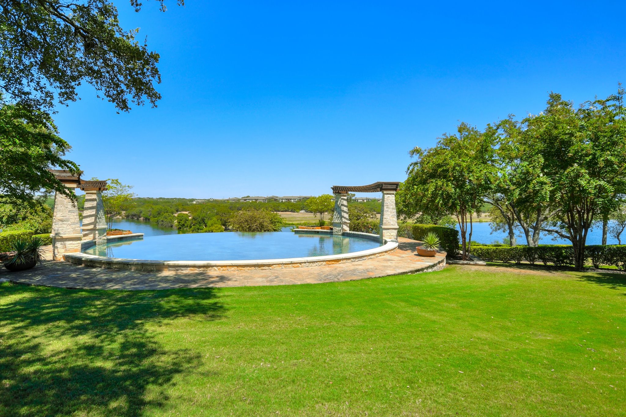 14001 Avery Ranch Boulevard, Unit 202 Austin, TX 78717 - Photo 24 of 30 Expansive green lawn bordering a stone-edged infinity-edge pool