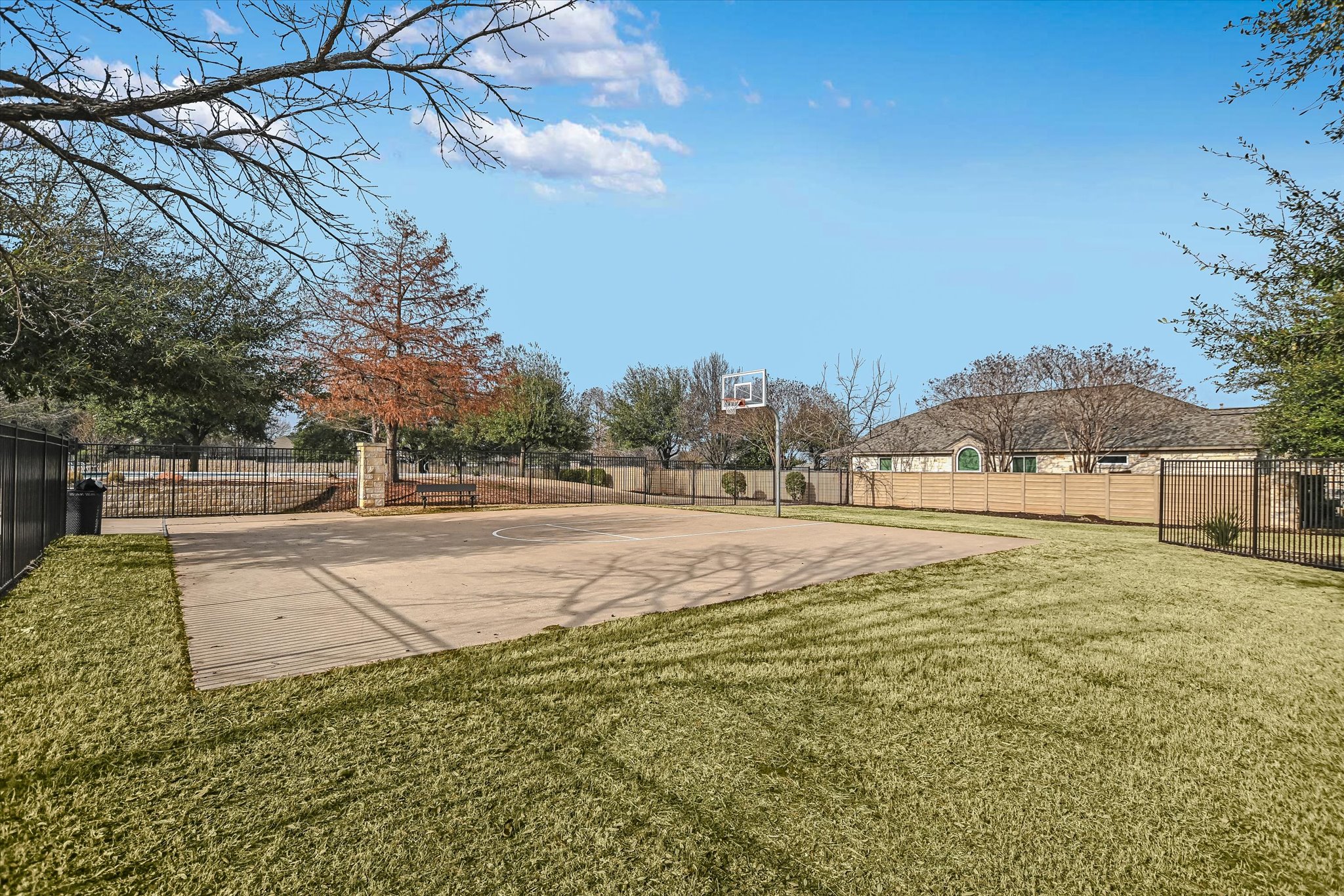 14001 Avery Ranch Boulevard, Unit 202 Austin, TX 78717 - Photo 27 of 30 Outdoor concrete sports court featuring a basketball hoop, surrounded by manicured lawn and mature trees