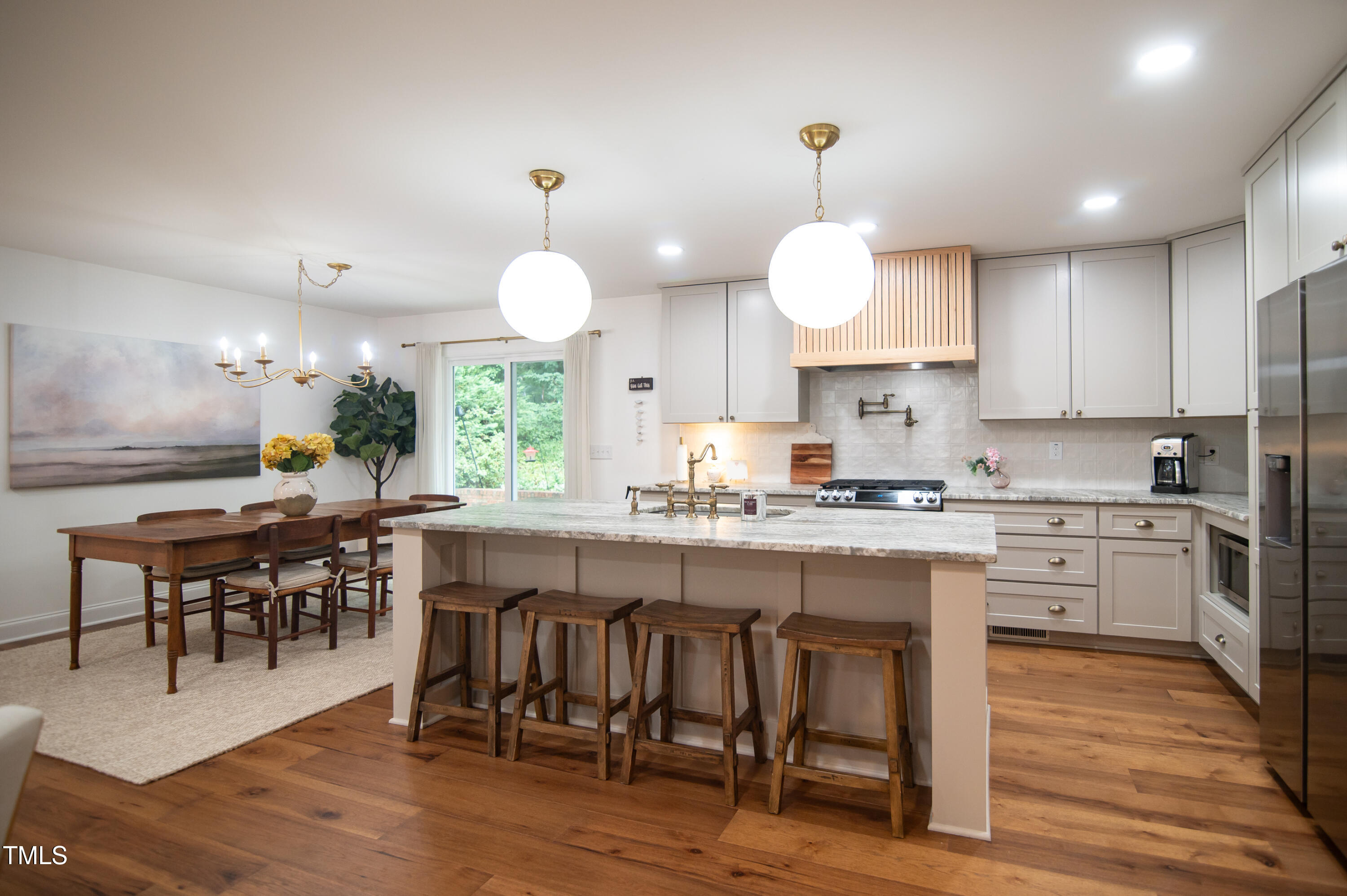 5012 Skidmore Street Raleigh, NC 27609 - Photo 5 of 27 a kitchen with stainless steel appliances granite countertop a stove top oven a refrigerator a dining table and chairs with wooden floor