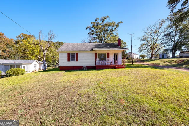 a view of a house with a big yard and large trees