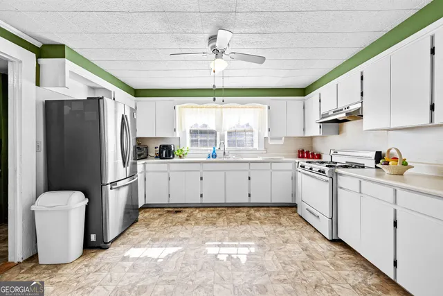 a kitchen with granite countertop white cabinets white appliances a sink and a window