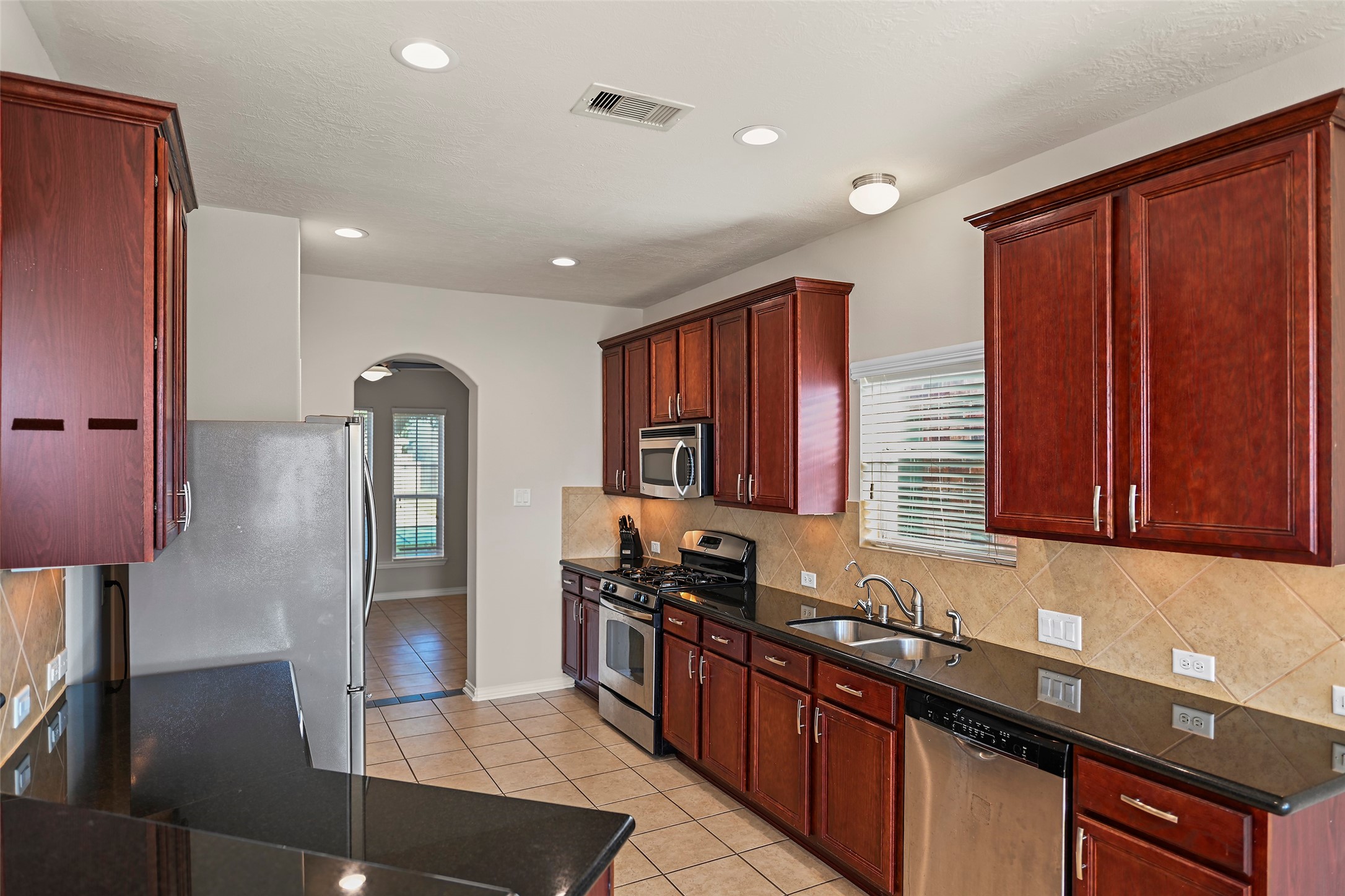 8323 Rudy Brook Way Spring, TX 77379 - Photo 11 of 35 a kitchen with stainless steel appliances granite countertop a stove a sink and a refrigerator