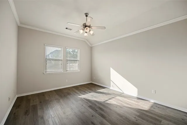 an empty room with wooden floor chandelier fan and windows