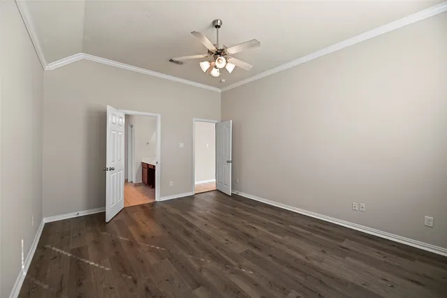 a view of an empty room with chandelier fan and wooden floor