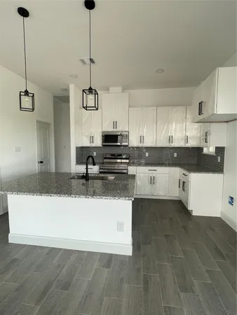 a kitchen with stainless steel appliances granite countertop a sink a stove a microwave and white cabinets