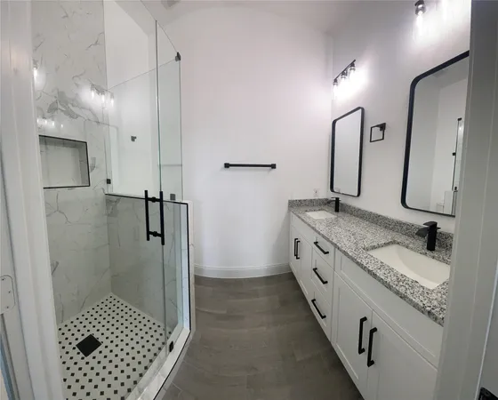 a bathroom with a granite countertop sink a mirror and shower