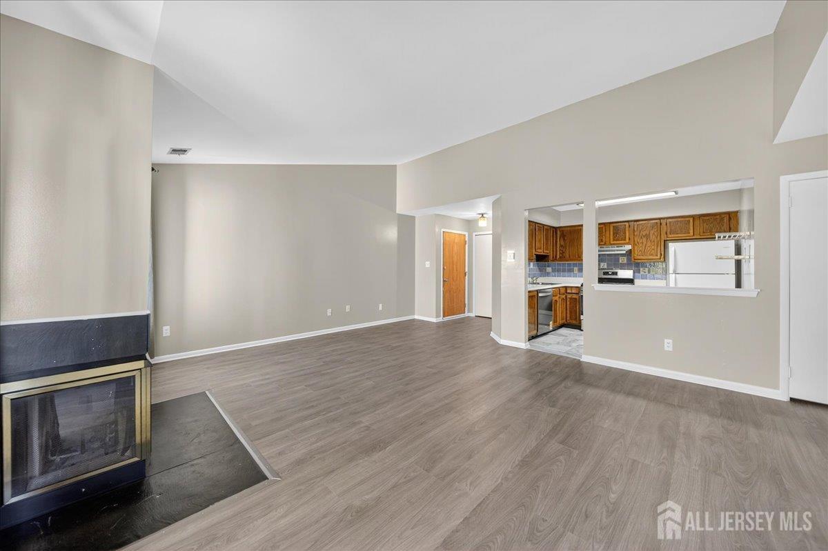 306 Trinity Court, Unit 12 Princeton, NJ 08540 - Photo 3 of 26 a view of a kitchen and an empty room with wooden floor and a fireplace