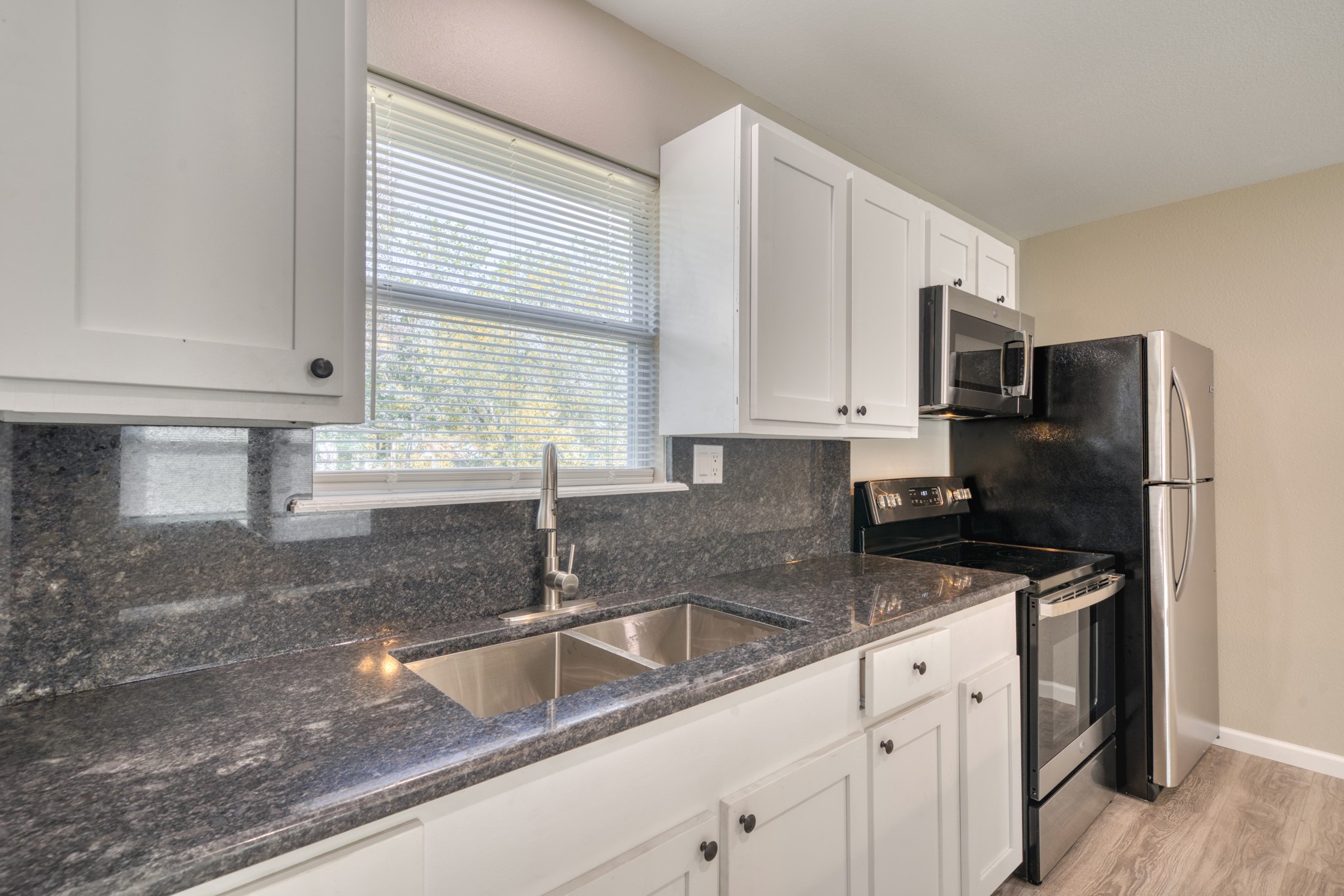 9337 Ash Street Midway, TX 75852 - Photo 9 of 28 a kitchen with granite countertop a sink a refrigerator a window and cabinets