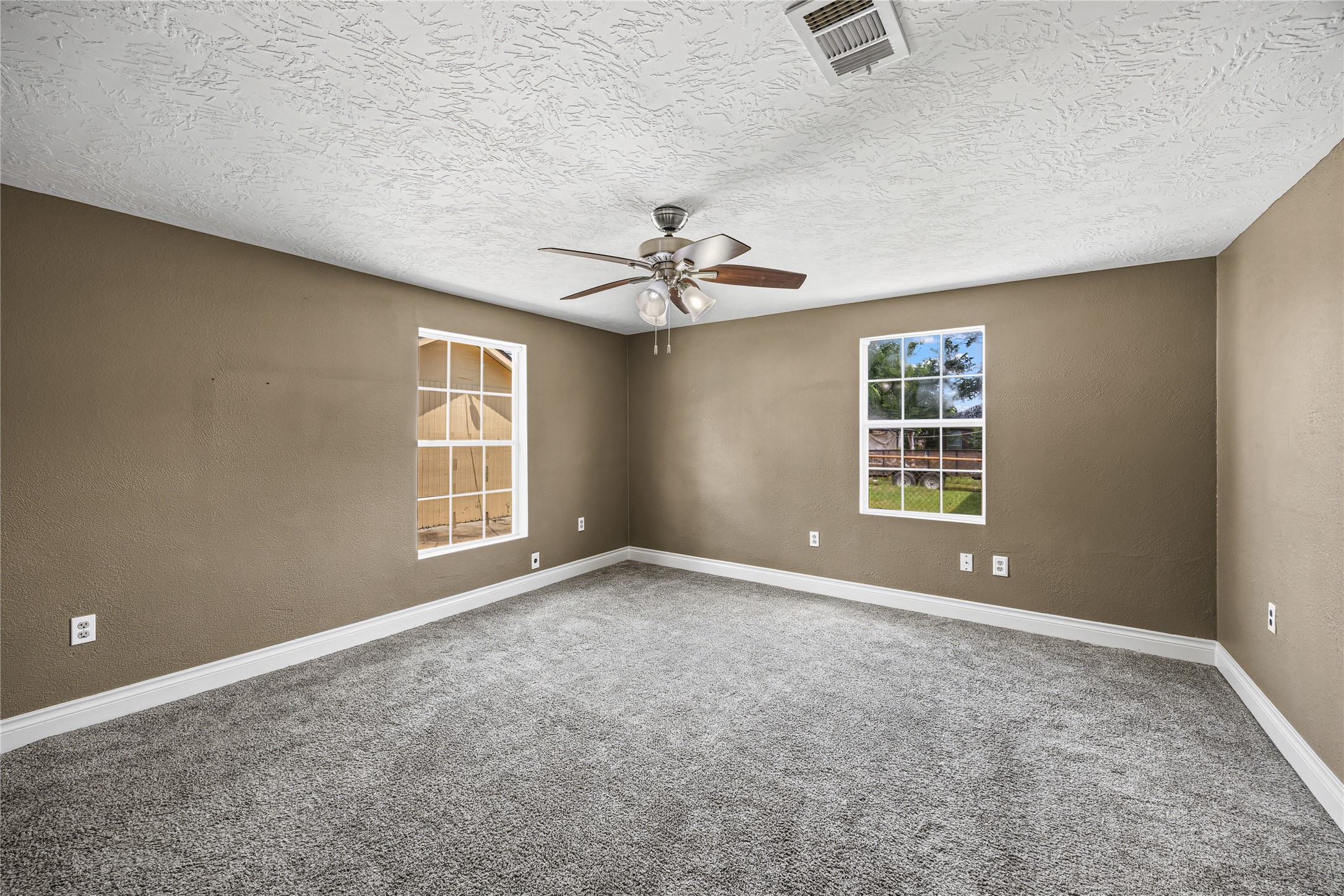 10221 Flaxman Street Houston, TX 77029 - Photo 10 of 20 an empty room with windows and ceiling fan