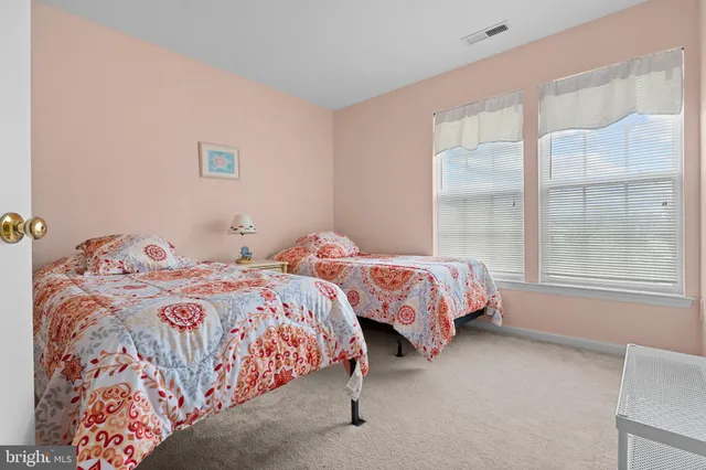 a bedroom with two beds and next to a window