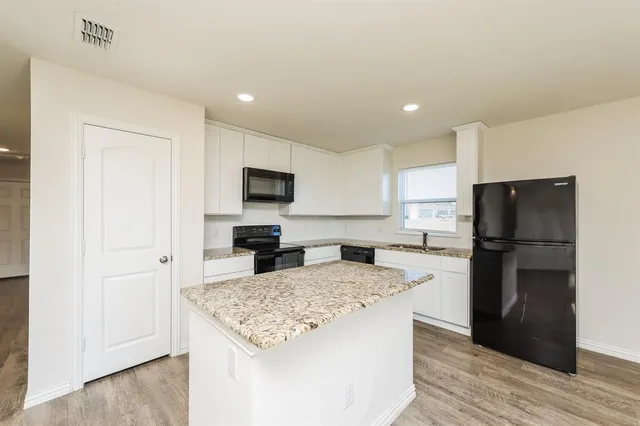 a kitchen with a refrigerator a stove a microwave and white cabinets