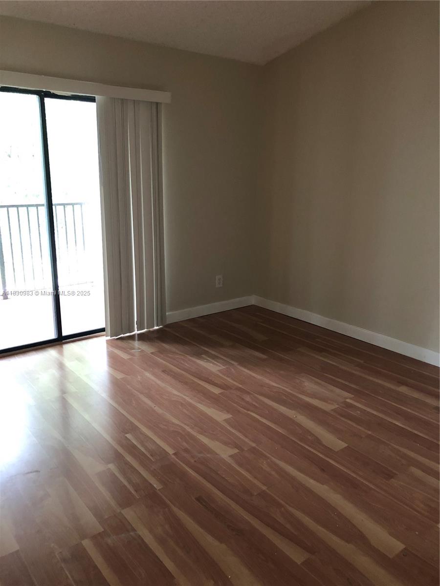 620 South Park Road, Unit 332 Hollywood, FL 33021 - Photo 4 of 6 an empty room with wooden floor and windows with curtains