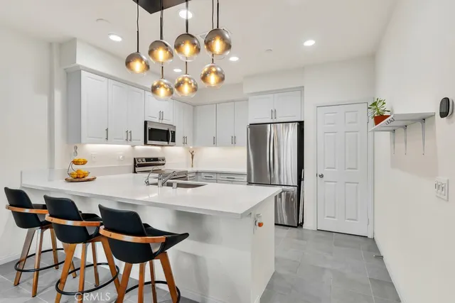 a kitchen with stainless steel appliances granite countertop a sink dishwasher a refrigerator oven a dining table and chairs with wooden floor