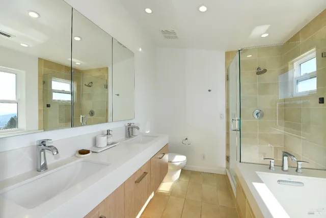 a bathroom with a sink double vanity granite tub shower and a mirror