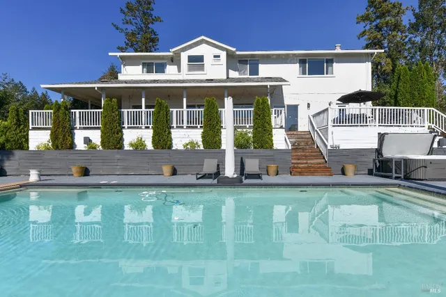 a view of a house with pool plants and large trees
