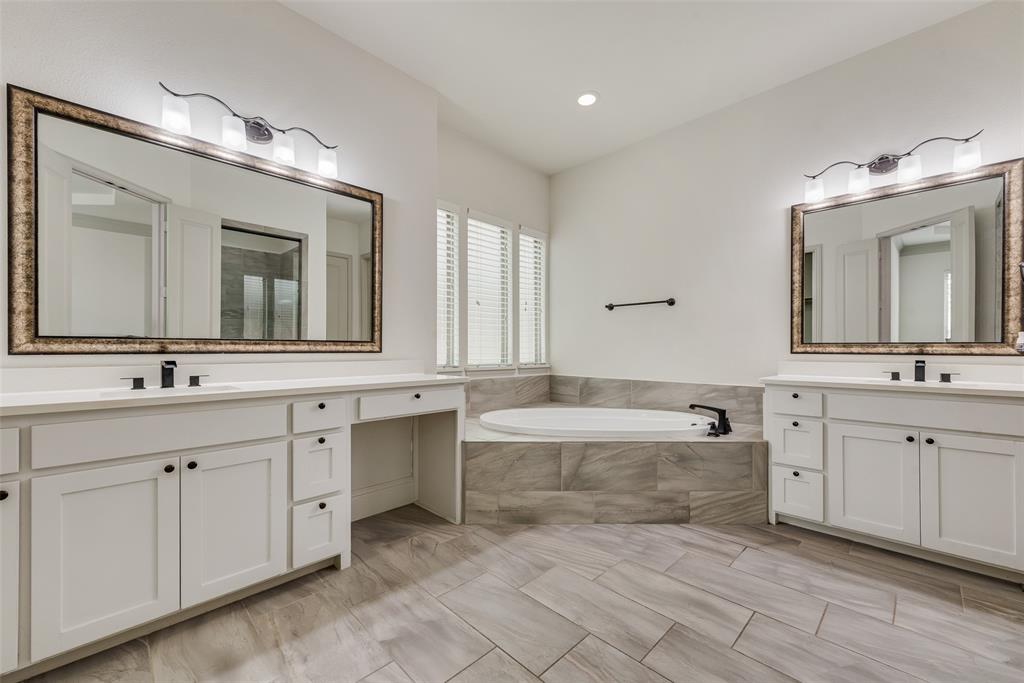 2021 Calisto Way Allen, TX 75013 - Photo 21 of 34 Dual vanity with white cabinetry and integrated sinks, complemented by a corner soaking tub with tiled surround