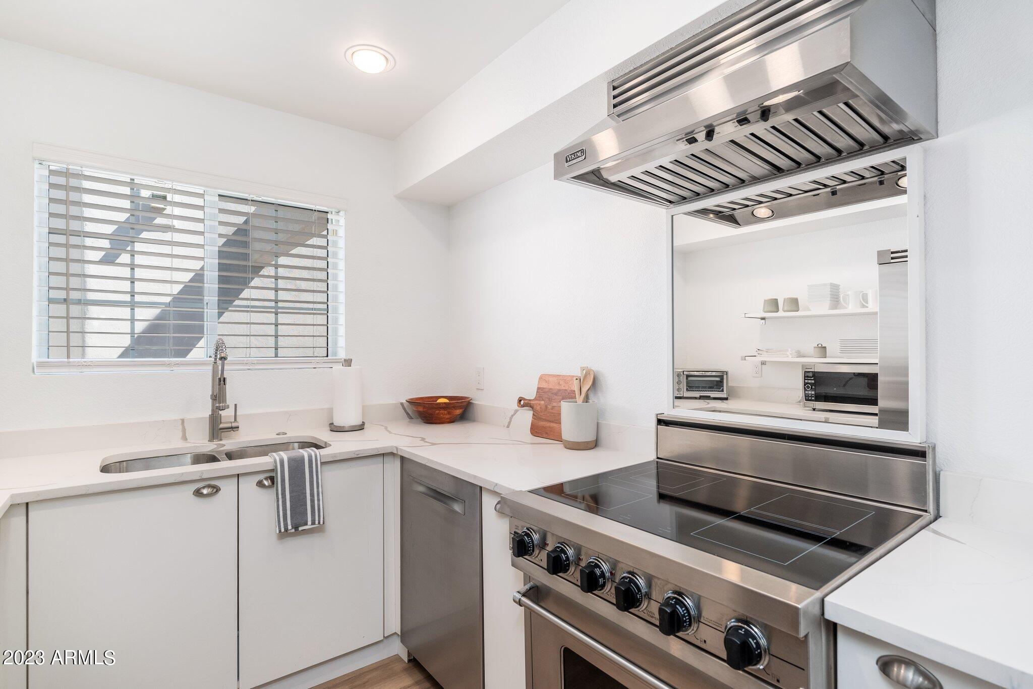 7710 East Gainey Ranch Road, Unit 259 Scottsdale, AZ 85258 - Photo 11 of 48 a kitchen with stainless steel appliances a sink a stove and white cabinets