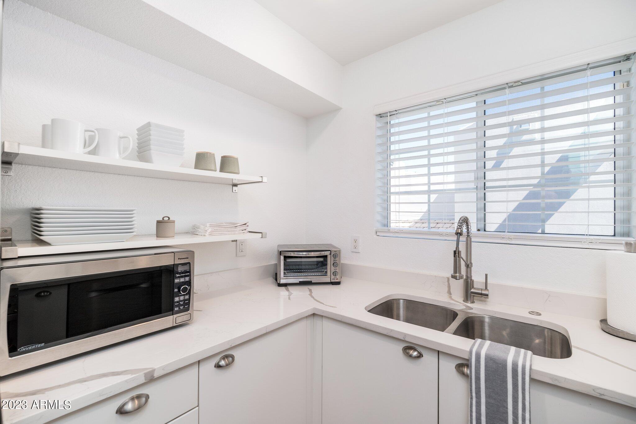 7710 East Gainey Ranch Road, Unit 259 Scottsdale, AZ 85258 - Photo 12 of 48 a kitchen with stainless steel appliances a sink a stove and white cabinets