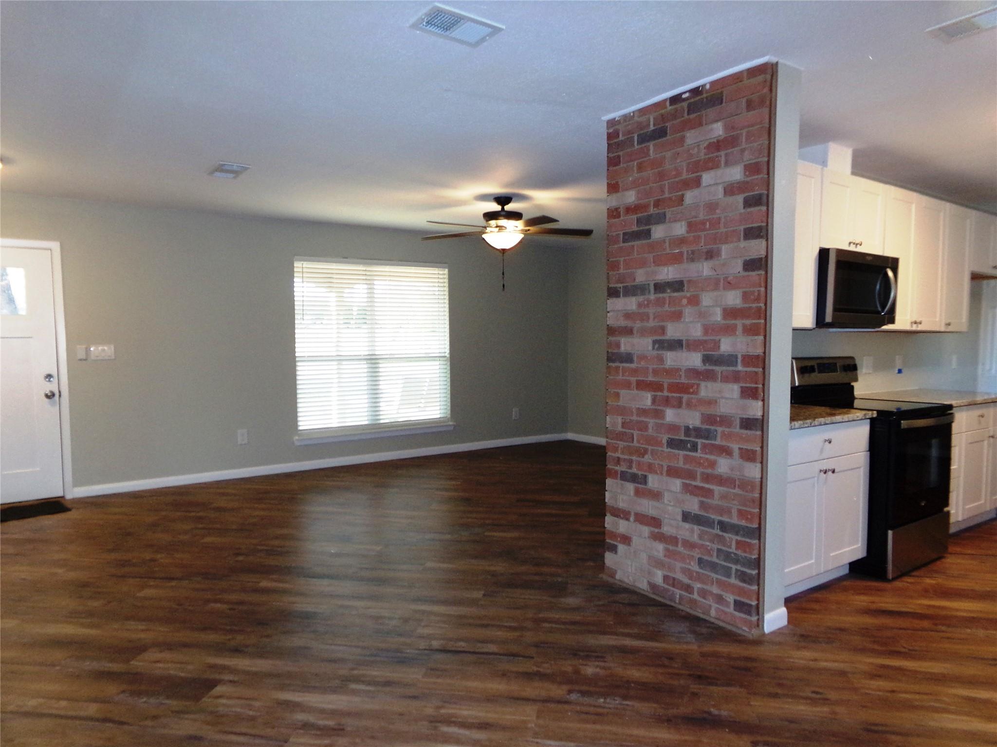 139 Farm To Market 696 Elgin, TX 78621 - Photo 12 of 27 Kitchen with stainless steel appliances, white cabinetry, dark wood-style flooring, light stone countertops, and ceiling fan