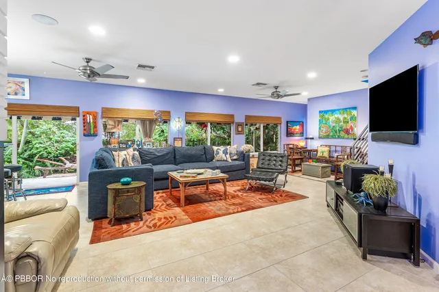 a living room with furniture a flat screen tv and floor to ceiling window