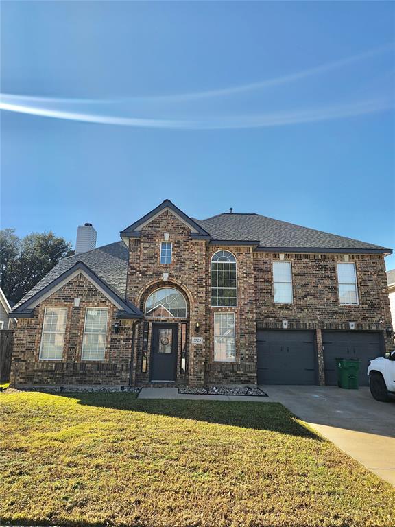 View of front facade with a front lawn, brick siding, concrete driveway, a garage, and roof with shingles