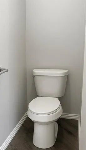 a white toilet sitting next to a white wall