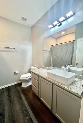 a bathroom with a granite countertop sink a toilet and a mirror