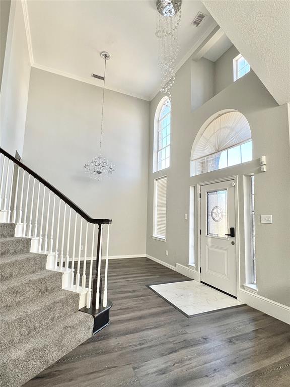 5729 Christy Lane Haltom City, TX 76137 - Photo 22 of 24 Entrance foyer featuring a chandelier, ornamental molding, a high ceiling, stairs, and dark wood-style floors