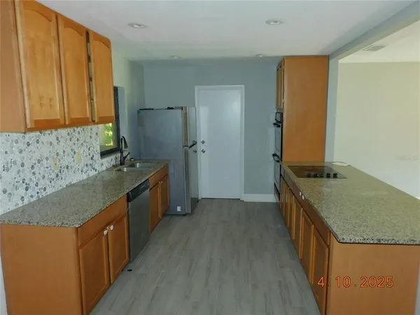 a kitchen with stainless steel appliances granite countertop a stove a sink a refrigerator and a wooden cabinets