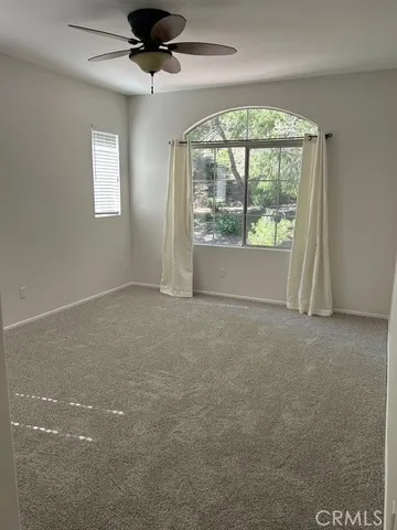 an empty room with a ceiling fan and window